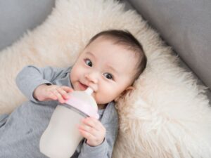 bé gái cầm bình sữa